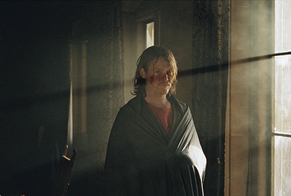 Caleb Landry Jones in a dimly lit room